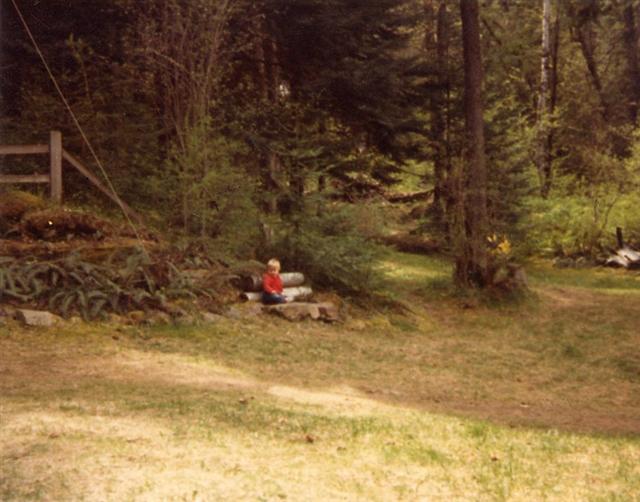 Margaret sitting near the path to the cabin.  The cabin is uphill to the left.  Spring 1982